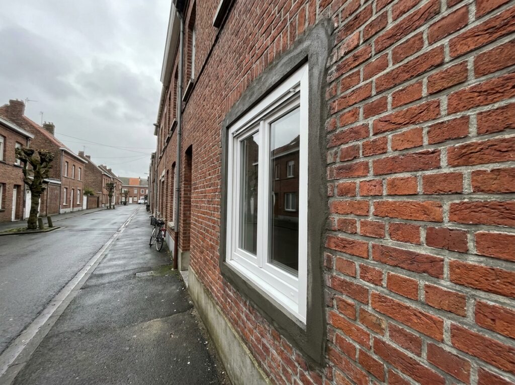 Fenêtre PVC double vitrage nouvellement installée sur une façade en briques à Dunkerque
